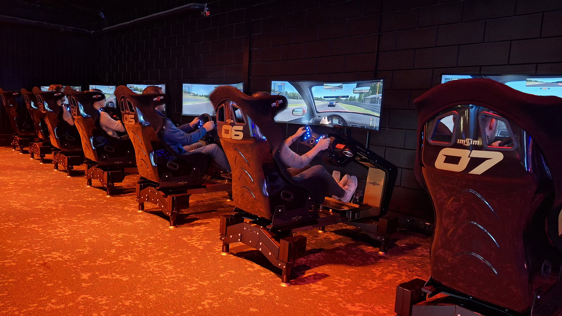 Seven numbered ImSim simulators in a row at Duinrell, with guests racing on them.